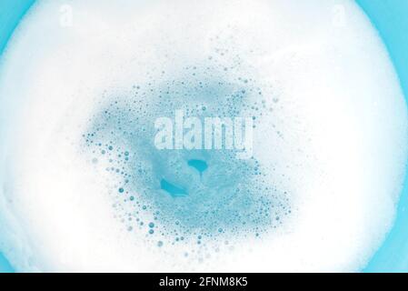 Foam on surface of water in blue plastic basin. Foam as texture or background. Stock Photo