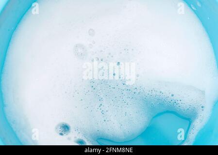 Foam on surface of water in blue plastic basin. Foam as texture or background. Stock Photo