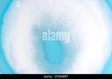 Foam on surface of water in blue plastic basin. Foam as texture or background. Stock Photo