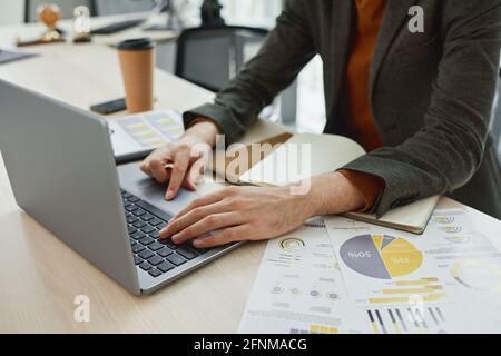 Close-up of office worker sitting at his workplace and typing on laptop computer he working online at office Stock Photo