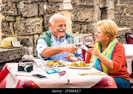 Senior couple having fun and eating at restaurant during travel - Mature man and woman wife in old city town bar during active elderly vacation Stock Photo