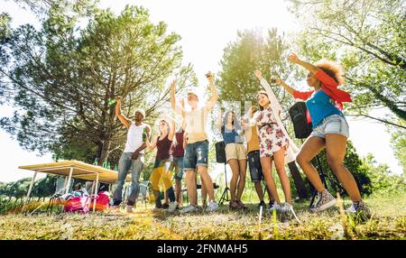 Multiracial friends having fun at barbecue pic nic garden party - Friendship multicultural concept with young happy people drinking and dancing Stock Photo
