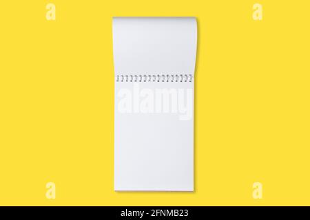 Schoo or office notebook on a yellow background. Mock up of spiral notepad on a table. Stock Photo