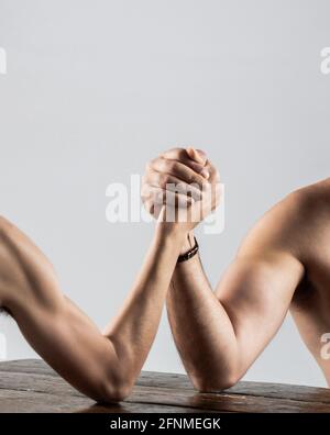 Arms wrestling thin hand, big strong arm in studio. Two man's hands clasped arm wrestling, strong and weak, unequal match. Arm wrestling. Heavily