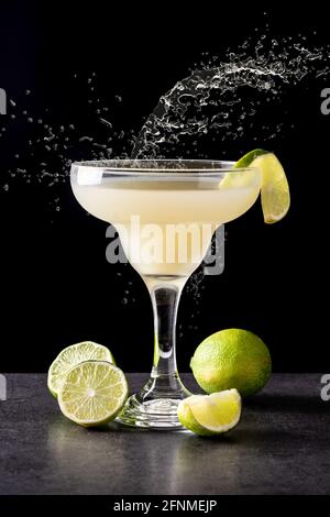 Classic daiquiri cocktail splashing in glass on black background Stock Photo