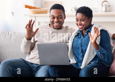 Black couple having videocall using laptop waving hands Stock Photo