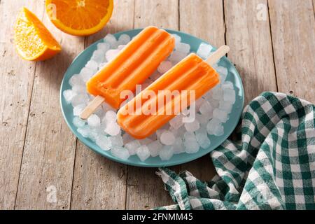 Orange popsicles on blue plate on wooden table Stock Photo