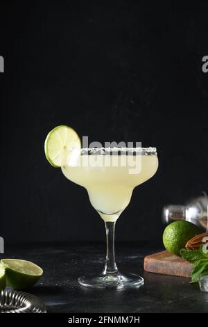 Classic Margarita cocktail with lime and ice cube on black background. Vertical orientation. Freshness summer alcoholic beverage. Homemade Margarita c Stock Photo