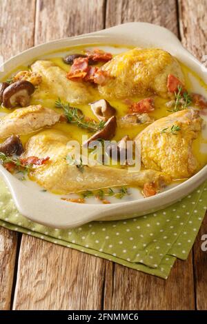 Alsace Coq au vin Riesling chicken in white wine with cream and mushrooms close-up in a saucepan on the table. Vertical Stock Photo