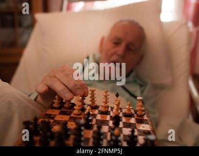 Close up of senior man's hand playing chess while lying in bed Stock Photo