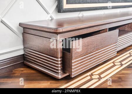 Elegant commode for TV set made of veneer and solid oak lumber toned in dark brown color on wood block parquet floor closeup Stock Photo