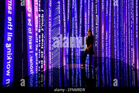 A Victoria and Albert Museum employee stands within a space which interprets the concept of the looking glass, part at the Alice: Curiouser and Curiouser exhibition at the Victoria and Albert Museum in London. Picture date: Tuesday May 18, 2021. Stock Photo