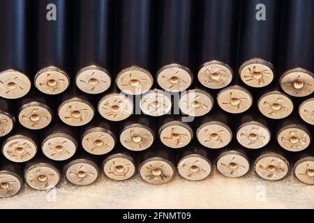 Large pile of new turned black legs for furniture assembling lie on floor in light carpentry workshop extreme close view Stock Photo