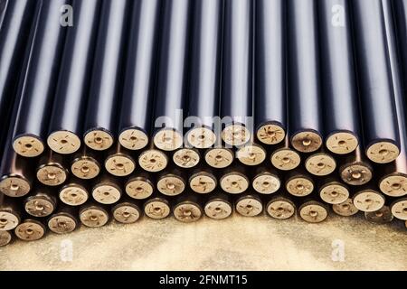 Large pile of new turned black legs for furniture assembling lie on floor in light carpentry workshop extreme close view Stock Photo