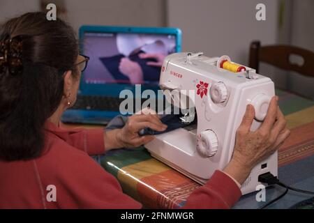 CASERTA, ITALY - Feb 08, 2021: Caserta, Italy, February 08th 2021, Grandma taking a video tutorial on how to learn to use the sewing machine Stock Photo