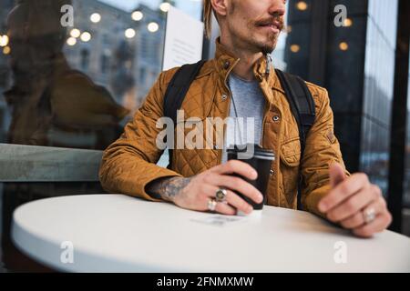 Bearded tattooed man having coffee outdoors alone Stock Photo