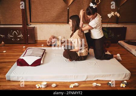 Woman spa worker pulling female arm during Thai massage Stock Photo