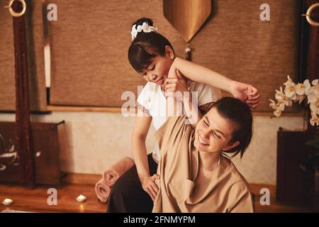 Female massage practitioner compressing side of joyful customer Stock Photo