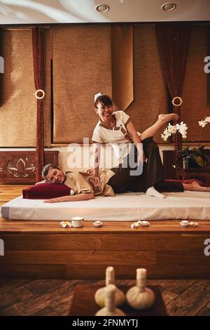 Thai female spa worker doing leg stretches for client Stock Photo