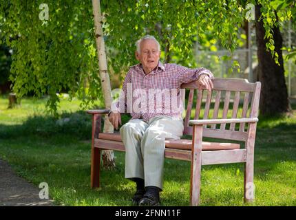 Senior unhappy man sitting on bench in park in summer time Stock Photo