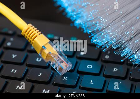 Internet cable, RJ-45 plug on laptop keyboard. High speed fiber optic internet concept Stock Photo