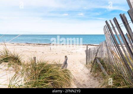 Fenced path through sand dunes to a deserted sandy beach on a partly cloudy autumn day Stock Photo