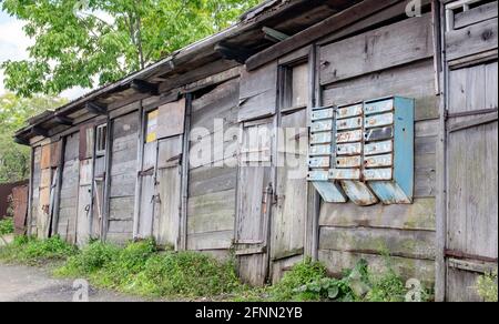 A row of old sheds made of dilapidated planks and a group of mailboxes on the doors. Stock Photo