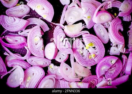 Red onion cut into pieces in a black pan Stock Photo