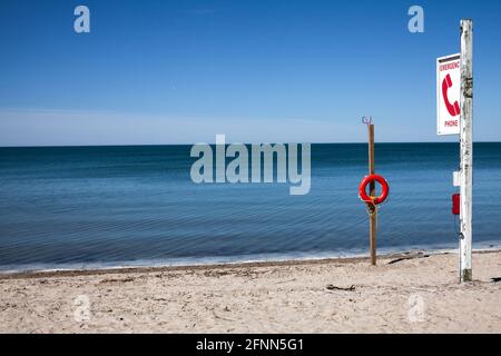 Emergency phone and lifeguard buoy on the beach with blue lagoon at Sandbanks, Ontario, Canada Stock Photo