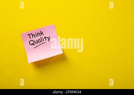 Think Quality word concept on sticky note against yellow background Stock Photo