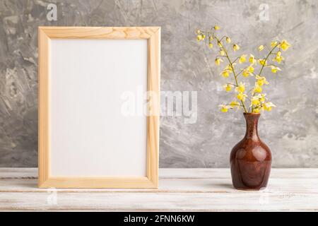Wooden frame with yellow barrenwort flowers in ceramic vase on gray concrete background. side view, copy space, still life, mockup, template, spring, Stock Photo