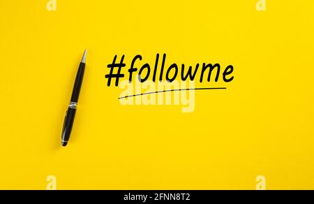 Word follow me or hashtag followme hand written with a black marker pen on yellow background. Stock Photo