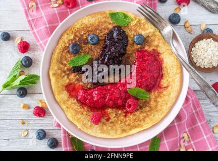 Healthy breakfast pancake made with gluten free oatmeal and served with pureed fresh berries on a plate. Stock Photo