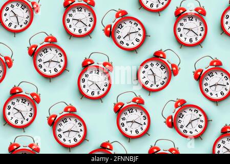 Top view of creative pattern made of red alarm clocks on a blue background Stock Photo