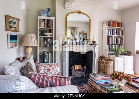 Gilt framed mirror on fireplace with bookcases in 19th century Victorian cottage. Stock Photo