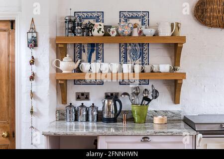 Collection of chinaware on wooden shelves in 19th century Victorian cottage. Stock Photo