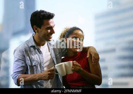 Happy young couple is drinking coffee and smiling while standing at the café Stock Photo