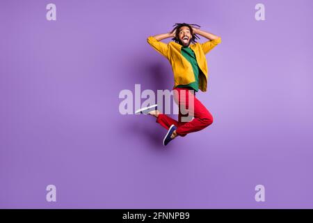 Full length photo of impressed dark skin man wear yellow shirt jumping high arms head isolated violet color background