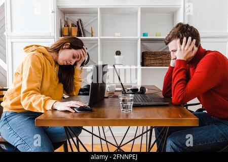 Tired man and woman working at home in the same room. Stock Photo