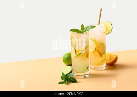 Two summer cold mojito cocktails with orange and lime slices on color white and beige background. Refreshing summer beverage. Stock Photo