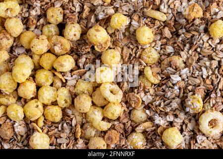 Organic homemade roasted crispy granola cereal with oatmeal and flaxseed flakes and crunchy corn balls and rings. Top view, flat lay muesli background Stock Photo