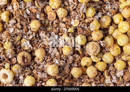 Organic homemade roasted crispy granola cereal with oatmeal and flaxseed flakes and crunchy corn balls and rings. Top view, flat lay muesli background Stock Photo