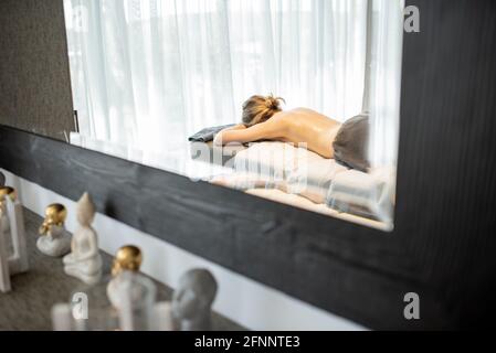 Beautiful woman lying in a spa salon and waiting for masseur for deep back massage and relaxation. Wellness and leisure time for health care together. Stock Photo