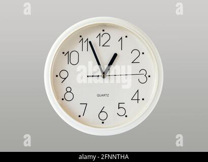 A generic white plastic quartz-action wall clock isolated on a grey background Stock Photo