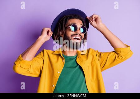 Portrait of cheerful dark skin man arms touch headwear look empty space isolate don purple color background Stock Photo