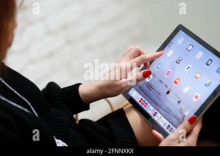 Woman choosing apps and icons on an Apple iPad digital tablet.  France. Stock Photo