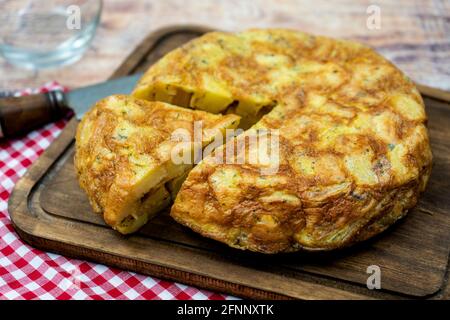 Typical Spanish omelette of potatoes or potatoes with a portion cut in a rustic environment. Spanish Cuisine. Stock Photo