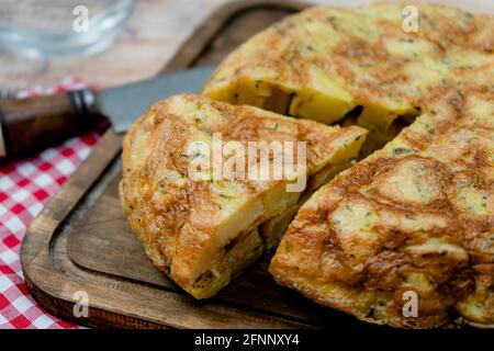Close-up of a cut portion of a typical Spanish potato or potato omelette in a rustic setting. Spanish Cuisine. Stock Photo