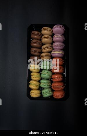 Box macaron yellow green red black brown purple black background Stock Photo