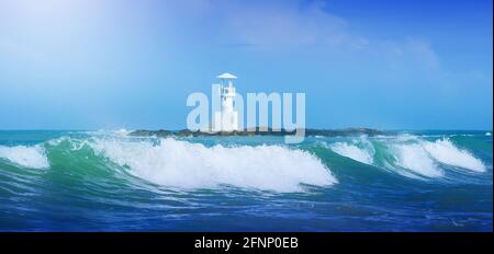 Rushing ocean waves and the white lighthouse on the island blurred in the background. Khao Lak, Thailand. Focus on waves. Stock Photo